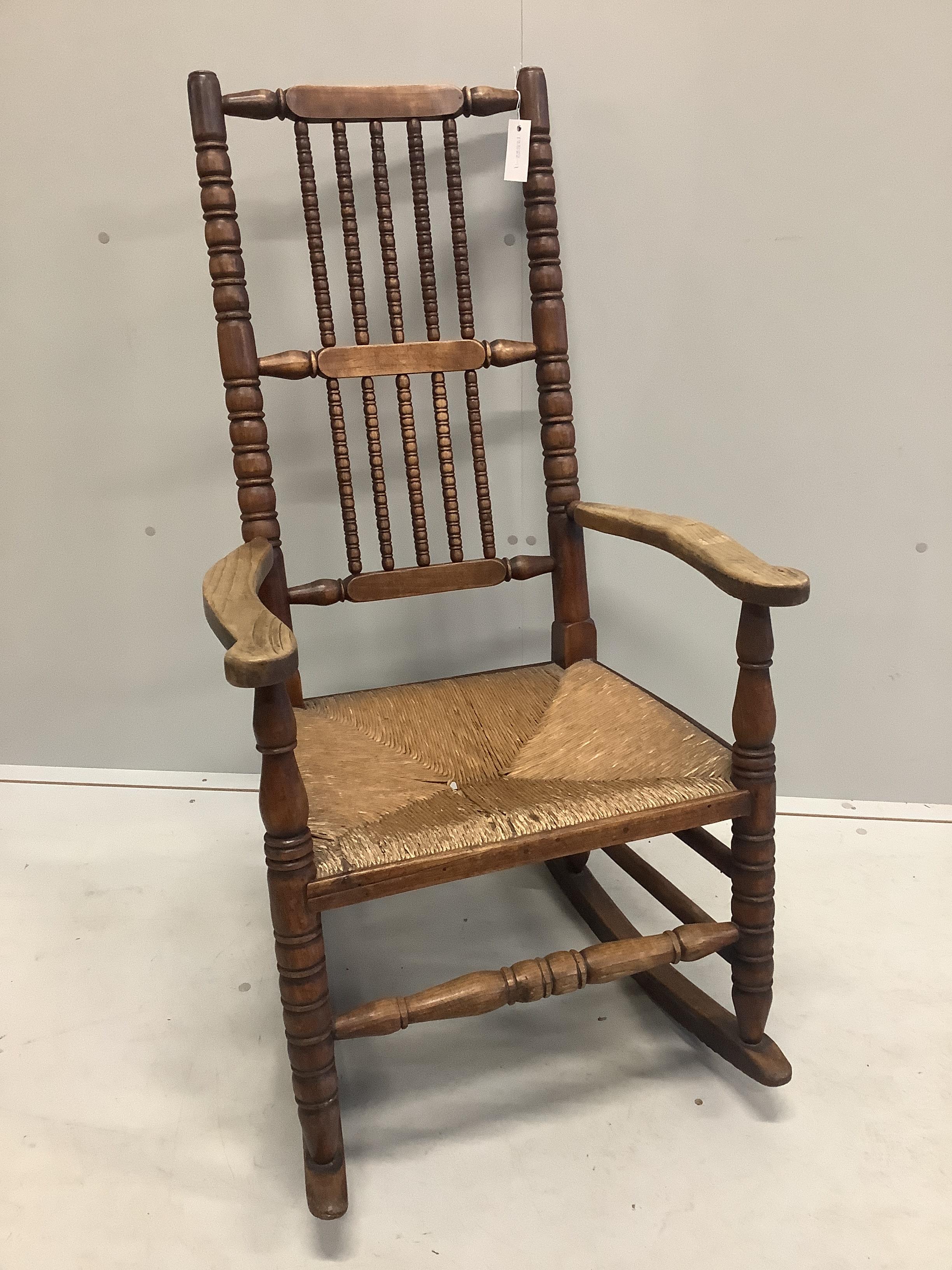 A late 19th century provincial fruitwood rush seat rocking chair, width 58cm, depth 46cm, height 110cm
